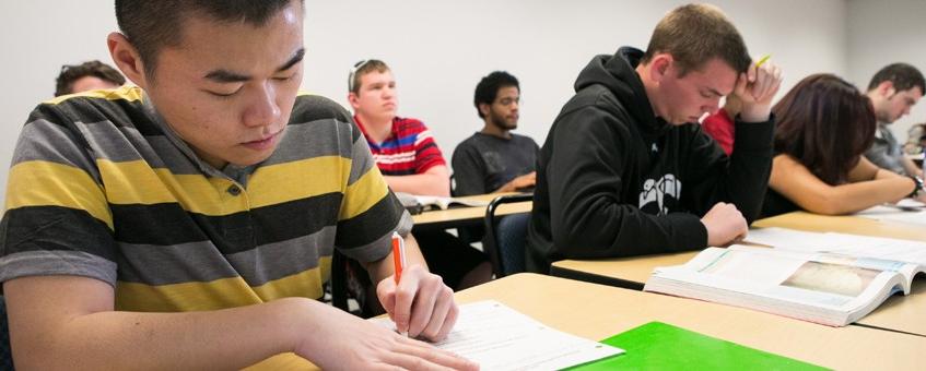 A marketing student taking notes in class.