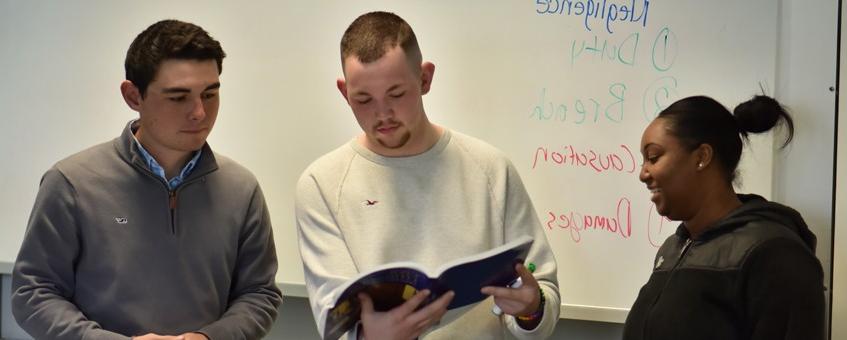 Three paralegal students looking at a textbook